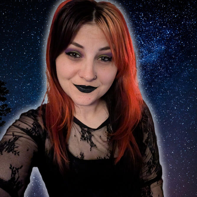 Girl with red and black hair over a starry night background. She has a lacey black shirt over a black crop top. She has black lipstick. She also has green and purple eyeshadow with dark winged eyeliner. She also has a black nose ring